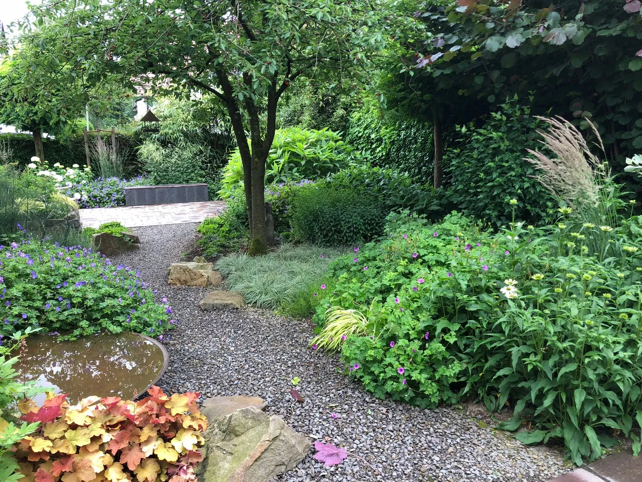 garten-unterberg-gartenkalender-september-schattengarten-staudenbeet-baumscheibe Schattiger Staudengarten mit Gräsern entlang eines Kieswegs